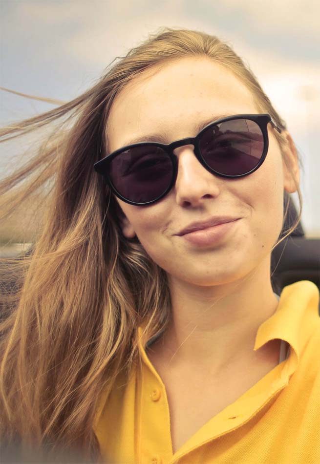 femme blonde cheveux souriante au vent et lunette de soleil